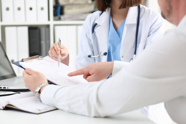 Ärztin hält silbernen Stift in der Hand und zeigt Block - Foto, Bild