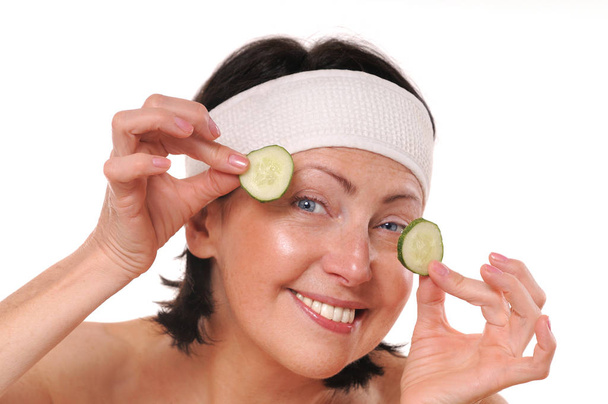 Mulher madura alegre segurando pedaços de pepino na frente de seus olhos
 - Foto, Imagem