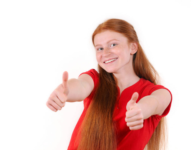 Menina adolescente de cabelo vermelho em uma camisa vermelha mostrando um polegar para cima em ambas as mãos
 - Foto, Imagem