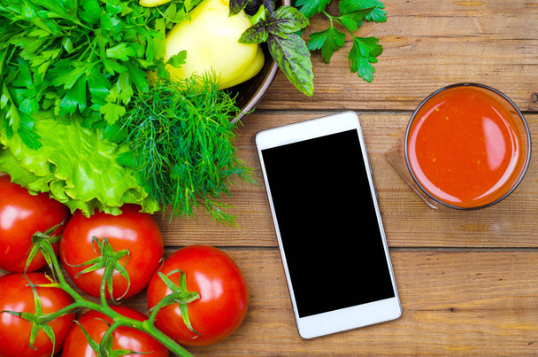 Fresh tomato juice, tomatoes and smartphone on a wooden table to - Zdjęcie, obraz