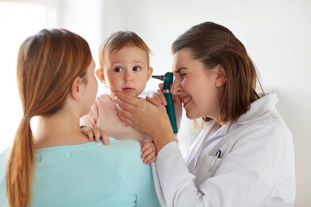 doctor with otoscope checking baby ear at clinic - Photo, Image