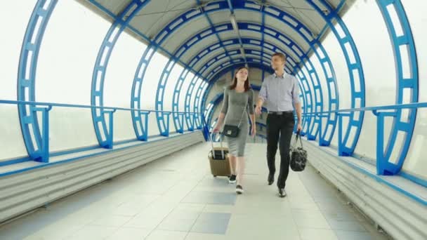 Business partners - a man and a woman go with luggage at the terminal of the station or airport. Business trip, team work - Imágenes, Vídeo
