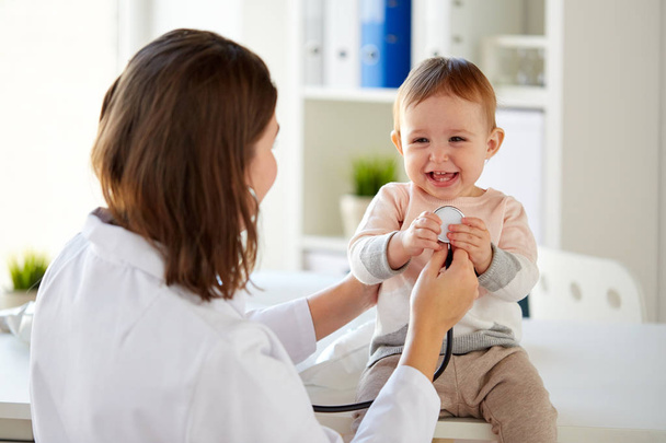 doctor with stethoscope and happy baby at clinic - Photo, Image