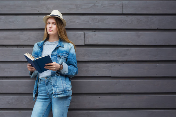 Teen woman read book outside wall - 写真・画像