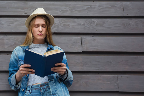 Teen woman read book outside wall - 写真・画像