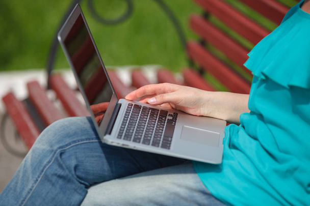 Young woman working on laptop in the park - 写真・画像