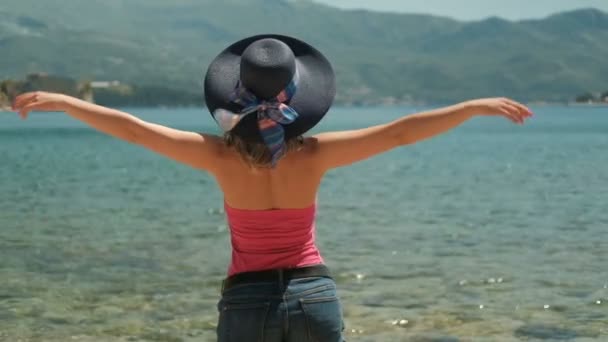 Vrouw met hoed tegoed aan de kust wierp gelukkig armen naar de kant. - Video