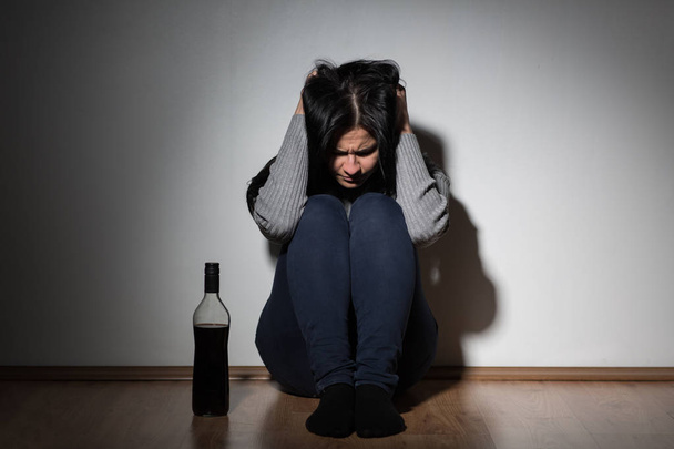 woman with bottle of alcohol crying at home - Photo, image