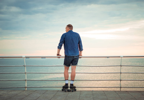 Young caucasian man roller skating with quad skates near the sea - Photo, image
