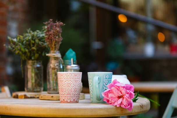 cups of tea and peony on wooden table in street cafe - Foto, Bild