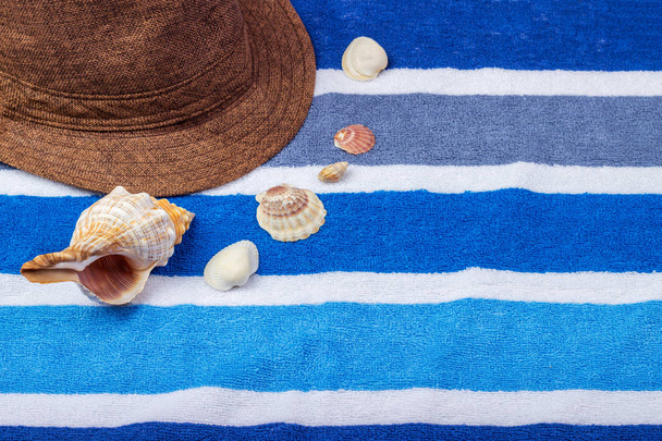 Uma composição de férias de verão em uma toalha de praia com conchas e um chapéu
. - Foto, Imagem