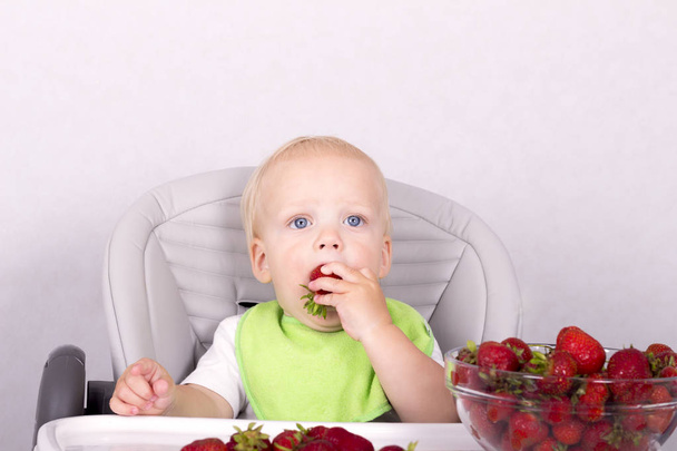かわいい幼児がイチゴを食べるします。面白い男の子は彼の腕でイチゴ - 写真・画像