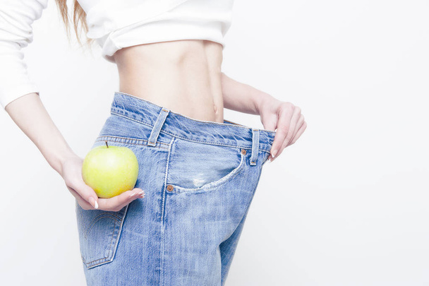 Giovane donna magra che tiene una mela e indossa jeans oversize
 - Foto, immagini