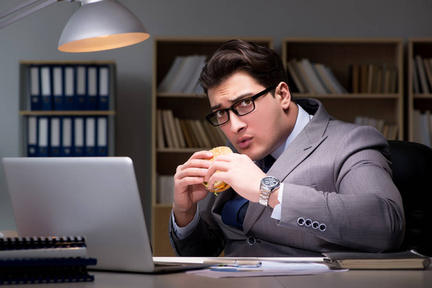 Homme d'affaires tard dans la nuit manger un hamburger - Photo, image