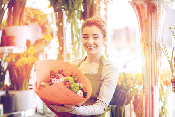 smiling florist woman with bunch at flower shop - Foto, Imagem