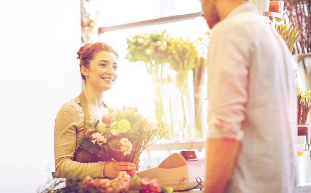 smiling florist woman and man at flower shop - Foto, Imagen