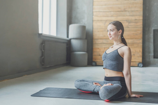 Młoda atrakcyjna kobieta praktykowania jogi, siedząc w padmasana - Zdjęcie, obraz