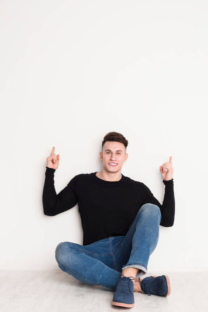 Young man points up at white studio background. - Foto, Bild