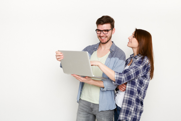 Couple décontracté faisant du shopping en ligne avec ordinateur portable, plan studio
 - Photo, image