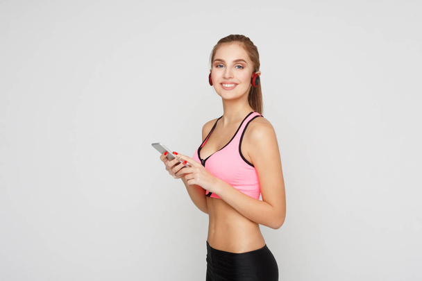 Dziewczynka fitness w słuchawki wybrać muzykę na telefon - Zdjęcie, obraz