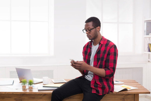 Giovane uomo d'affari nero fare una telefonata sul cellulare in ufficio bianco moderno
 - Foto, immagini