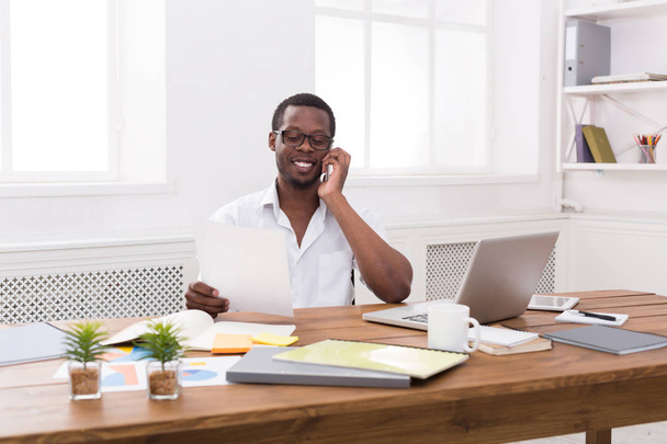Jeune homme d'affaires noir appeler téléphone mobile dans le bureau blanc moderne
 - Photo, image