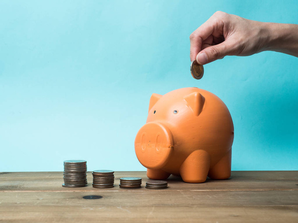 Woman Hand  putting coin into piggy bank for saving with pile of - Photo, image