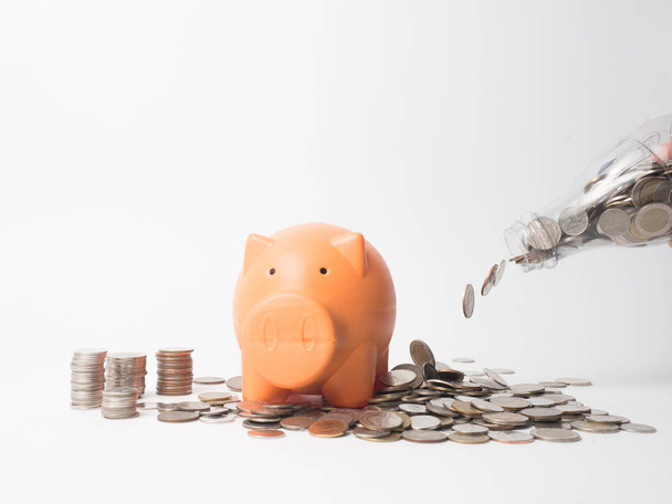 Woman Hand  putting coin into piggy bank for saving with pile of - 写真・画像