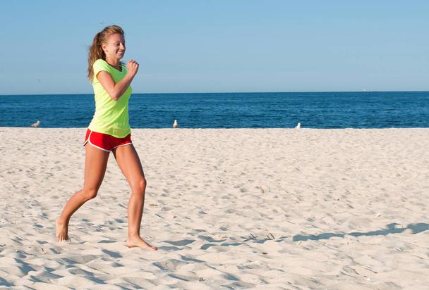 Running woman. Female runner jogging during outdoor workout on beach.  - Фото, зображення