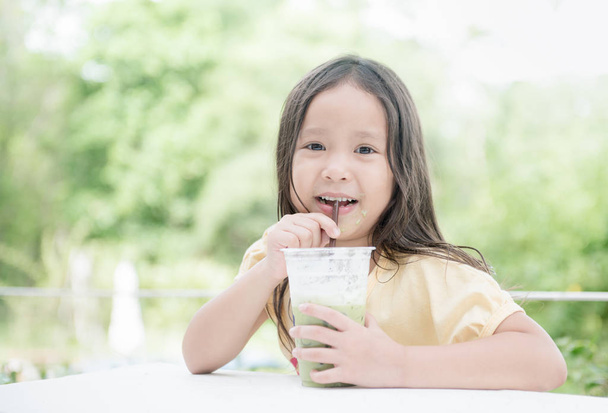 süße asiatische Mädchen trinken Eismilch grünen Tee - Foto, Bild