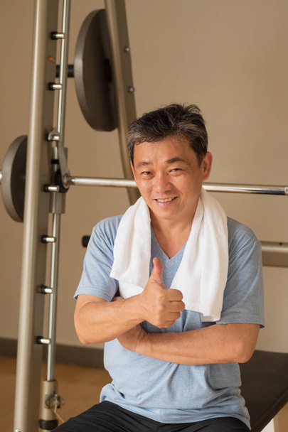 zdrowy, szczęśliwy starszy człowiek poćwiczyć w siłowni, co daje kciuk ge - Zdjęcie, obraz