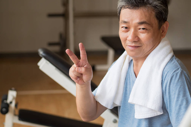 saudável, homem sênior feliz trabalhando no ginásio, dando no.2 dedo
 - Foto, Imagem