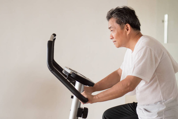 old senior man cycling, exercising, working out in gym with mode - Photo, Image