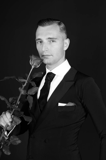 Business man with rose flower on black background - Foto, Imagen