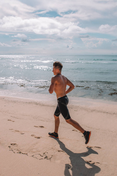 Jovem atleta musculoso treina na costa do Oceano Índico, Indonésia, Bali
 - Foto, Imagem