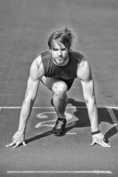athletic bearded man with muscular body stretching on running track - 写真・画像