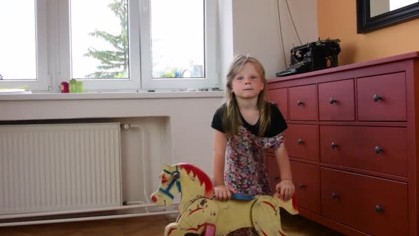 A menina gira balança no cavalo de baloiço. Smalll menina usa vestido florido. Conceito de infância
 - Filmagem, Vídeo