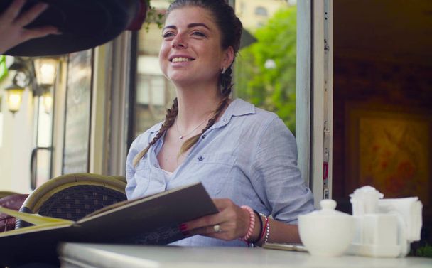 Портрет молодой женщины, читающей меню в кафе
 - Фото, изображение