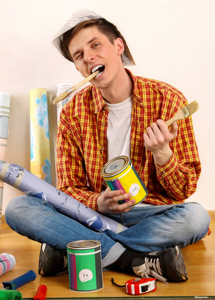 Repair home man holding paint roller for wallpaper. - 写真・画像