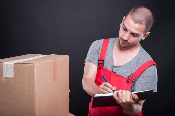 Mover guy looking at boxes writing in agenda - Φωτογραφία, εικόνα
