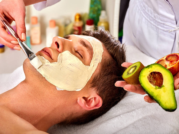 男性のための新鮮な果物からの顔のマスク。美容師は、スライスを適用します。. - 写真・画像