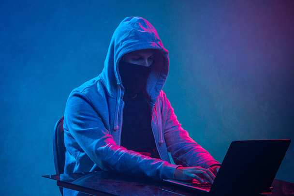 Zakapturzony haker komputerowy kradnie informacje z laptopem - Zdjęcie, obraz
