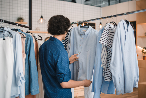 man choosing shirts in boutique - Foto, afbeelding