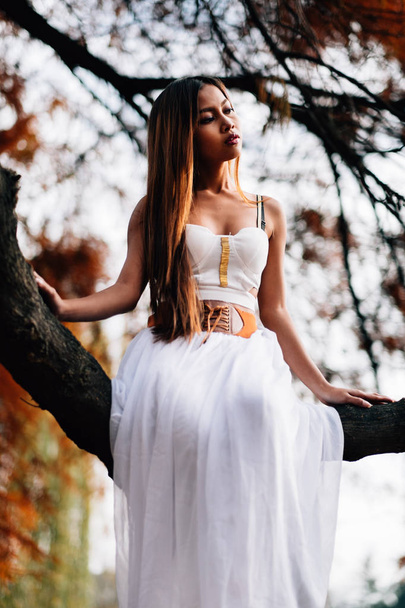 Фантастична молода жінка. красива фентезі дівчина фея з білим довгим платтям у вітряному осінньому парку
 - Фото, зображення