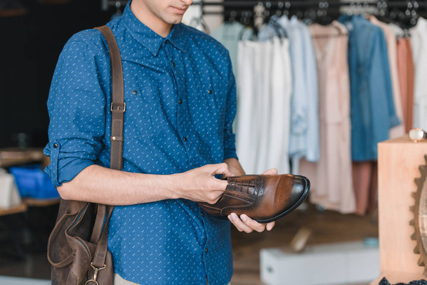 man holding shoe in boutique  - Фото, изображение
