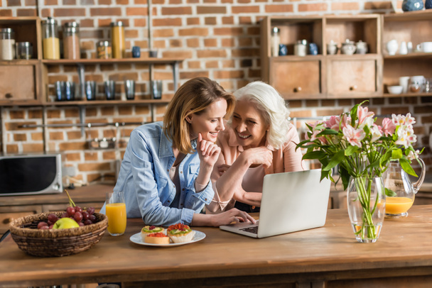 donne che utilizzano il computer portatile in cucina
 - Foto, immagini