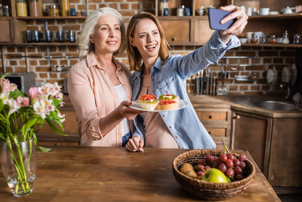 mujeres tomando selfie en cocina
 - Foto, Imagen