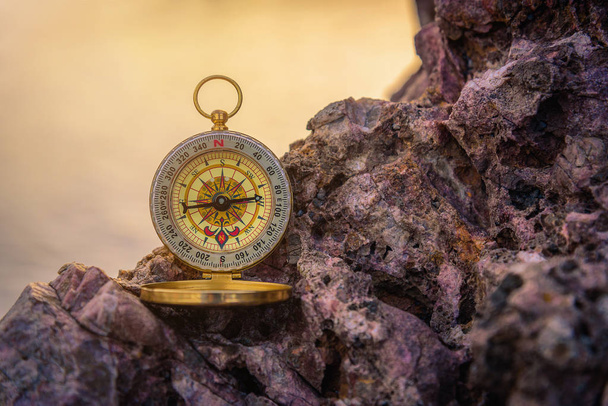 Analoginen kompassi hylätty kiviä hämärtynyt meri backg
 - Valokuva, kuva