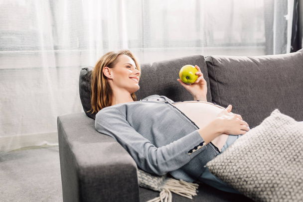 těhotná žena odpočívá na šedé rozkládací - Fotografie, Obrázek