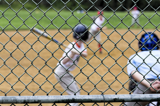 Nuorten baseball peli näkyy backstop
 - Valokuva, kuva